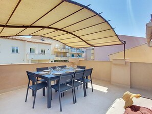 An outdoor dining area with a table set for four, surrounded by chairs, under a large umbrella. - Maison Lou Oustaou by Interhome (Sainte Maxime)
