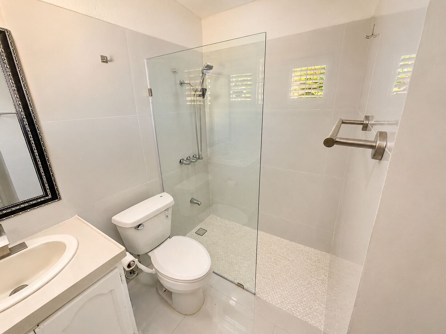 A modern bathroom with a glass shower enclosure, a toilet, and a sink.