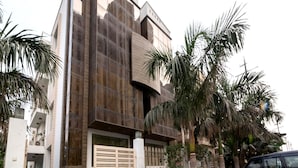 Un bâtiment moderne doté d’une façade originale, d’une entrée sécurisée et d’une voiture garée.
