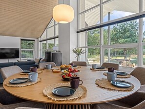 Een moderne eethoek met een ronde tafel, stoelen en een groot raam met uitzicht op het landschap.