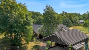 Ein modernes Gebäude mit geneigtem Dach, umgeben von Bäumen und einer Schotterauffahrt.