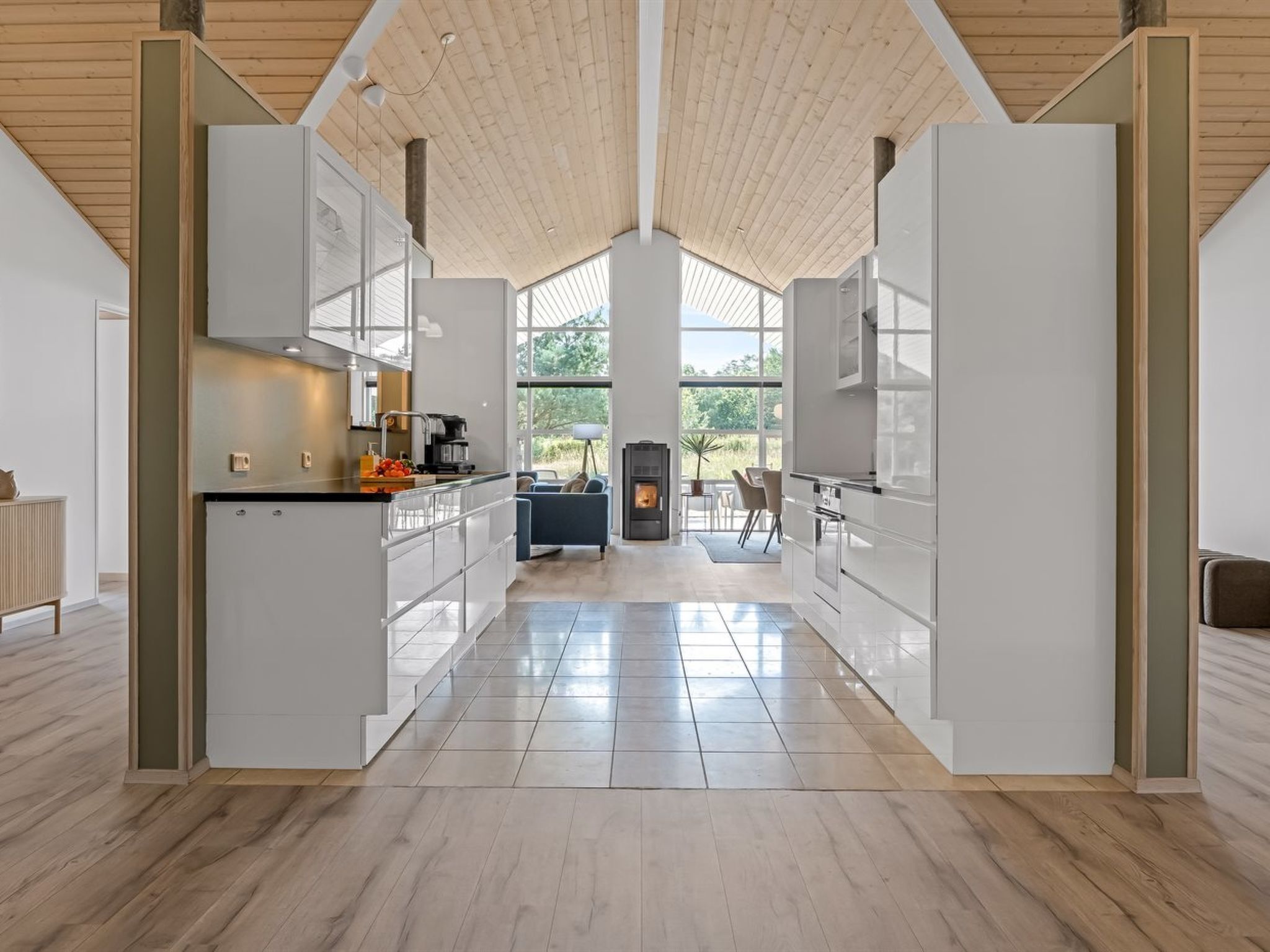 A modern kitchen with high ceilings, large windows, and a central fireplace.
