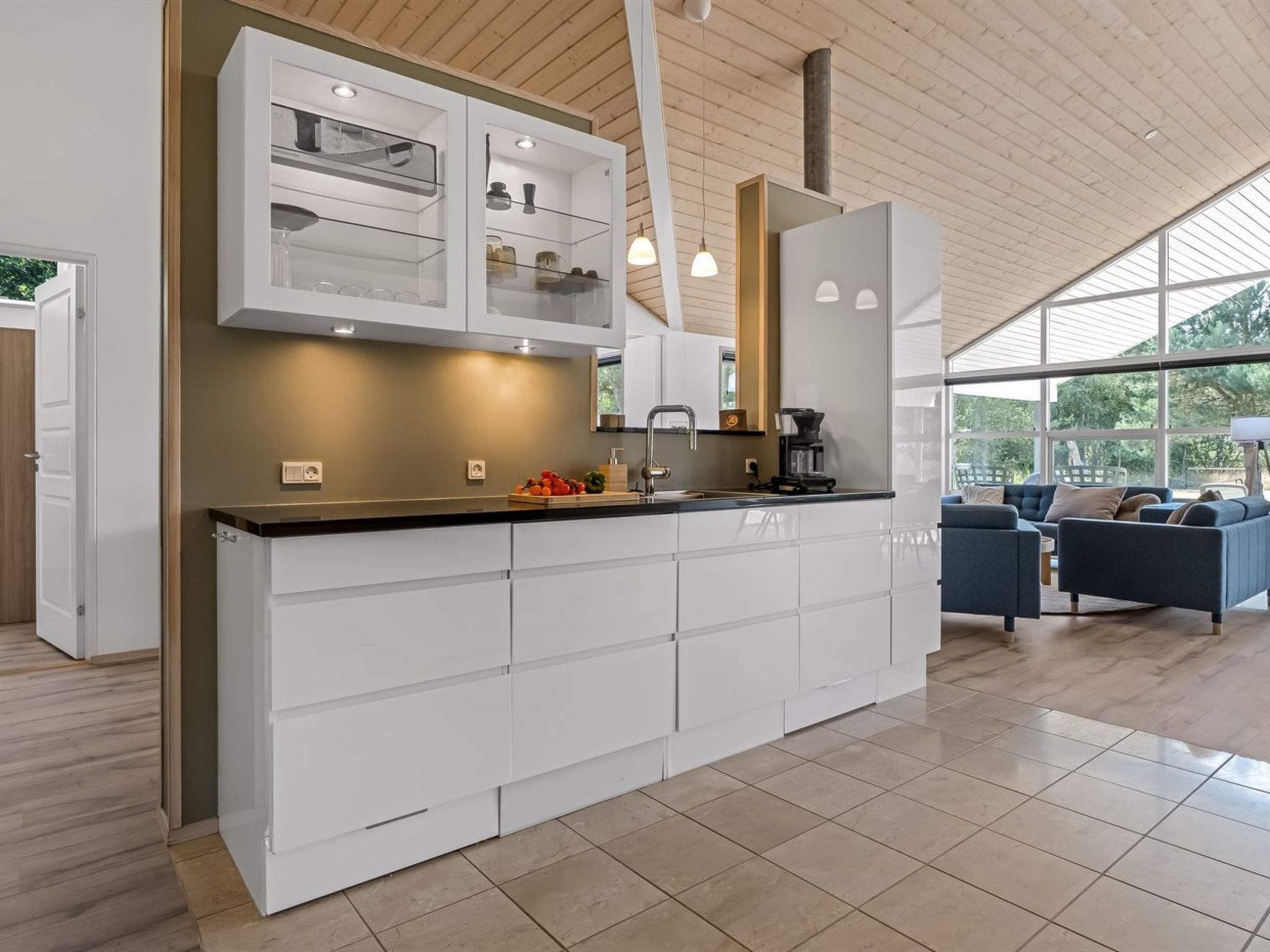 A modern kitchen with white cabinetry, a black countertop, and a built-in coffee station.