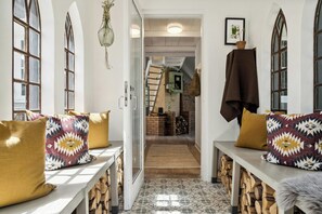 A hallway with a bench, a hanging plant, and a fireplace in the background. - Fine old details near Stubbe Lake (Ebeltoft)