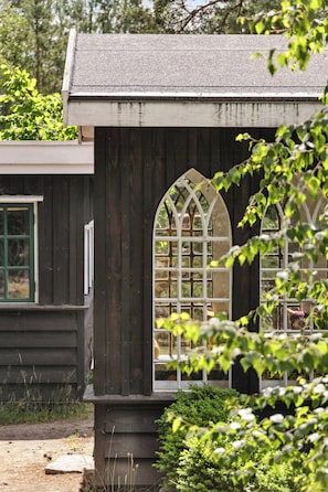 A wooden building with a dark facade and a window with a white frame. - Fine old details near Stubbe Lake (Ebeltoft)