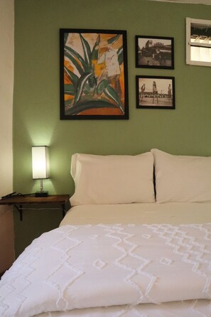 A hotel room with a bed, a nightstand with a lamp, and three framed pictures on the wall. - Sky · Quiet pedestrian alley · Downtown Oaxaca (Oaxaca de Juárez)