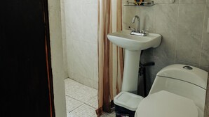 A small bathroom with a toilet, a pedestal sink, and a shower curtain. - Sky · Quiet pedestrian alley · Downtown Oaxaca (Oaxaca de Juárez)