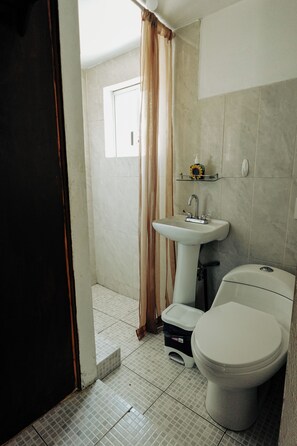A small bathroom with a toilet, a pedestal sink, and a shower curtain. - Sky · Quiet pedestrian alley · Downtown Oaxaca (Oaxaca de Juárez)