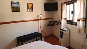 A room with a bed, a bench, a wall-mounted TV, and a window with curtains. - Sky · Quiet pedestrian alley · Downtown Oaxaca (Oaxaca de Juárez)