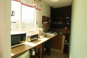A compact kitchen with a microwave, toaster, and gas stove. - Sky · Quiet pedestrian alley · Downtown Oaxaca (Oaxaca de Juárez)