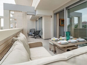 Ein Balkon mit einem Esstisch für zwei Personen, einem Korbsessel und einem Sessel.