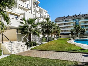Ein modernes Hotel mit Pool, Palmen und blauem Himmel.