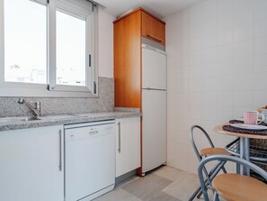 Een kleine keuken met een inbouwvaatwasser, een koelkast en een raam boven de gootsteen.