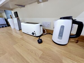 A kitchen with a white toaster, a kettle, and a microwave on a wooden countertop. - Glencarr by Interhome (Carrbridge)