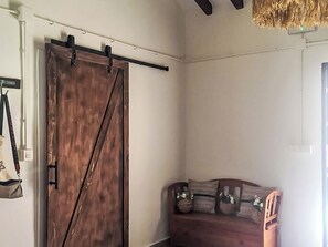 Ein Zimmer mit einer hölzernen Schiebetür im Stil einer Scheune, einem dunkelbraunen Sofa mit gemusterten Kissen und einer hängenden Tasche.