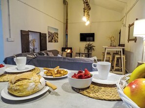 Ein gemütliches Wohnzimmer mit einer Couch, einem Tisch, der mit Speisen und Getränken gedeckt ist, und einem Kamin.