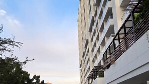 Un chemin menant à un bâtiment moderne doté de nombreux balcons, avec un ciel dégagé.