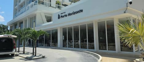 Un hotel moderno con un letrero llamativo, amplias ventanas y un estacionamiento.