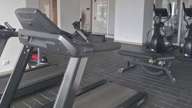 Une salle de sport équipée de tapis de course, de vélos d’appartement et d’autres appareils d’exercice.