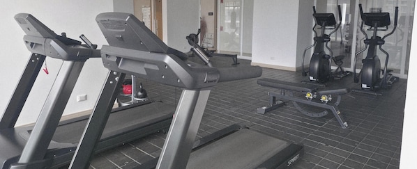 Un gimnasio con cintas de correr, bicicletas estáticas y equipo de ejercicio.