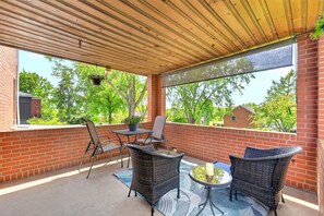 Eine überdachte Terrasse mit Korbmöbeln, einem Tisch und einem Blumentopf.