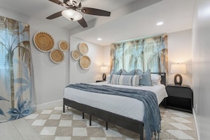 A bedroom with a bed, bedside tables, a ceiling fan, wall decor, and a window with curtains. - Heated Pool | Hot Tub | Enjoy Buccaneers & Rays (Tampa)
