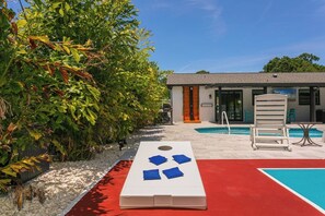 A pool area with a white lounge chair, a red mat, and a blue pool table. - Heated Pool | Hot Tub | Enjoy Buccaneers & Rays (Tampa)