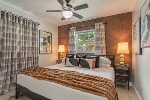 Ein Schlafzimmer mit einem Bett, zwei Nachttischen, einem Deckenventilator und einem Fenster mit Vorhängen.
