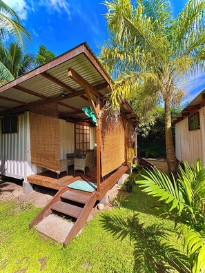 A bungalow with a covered porch, outdoor seating, and a small garden area. - FARE AIMEHO Fully equipped bungalow. An Authentic Stay in the ❤️ of Polynesia (Moorea-Maiao)