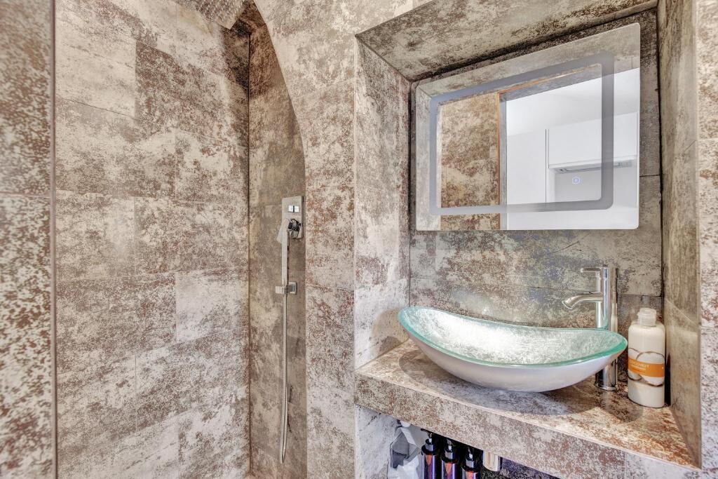 A bathroom with a glass bowl sink, a mirror, and a shower enclosure.