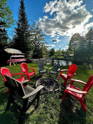 An outdoor seating area with Adirondack chairs and a fire pit. - Waterfront Kawartha Lakes A Frame Cottage with Hot Tub, Pet Friendly (Kawartha Lakes)
