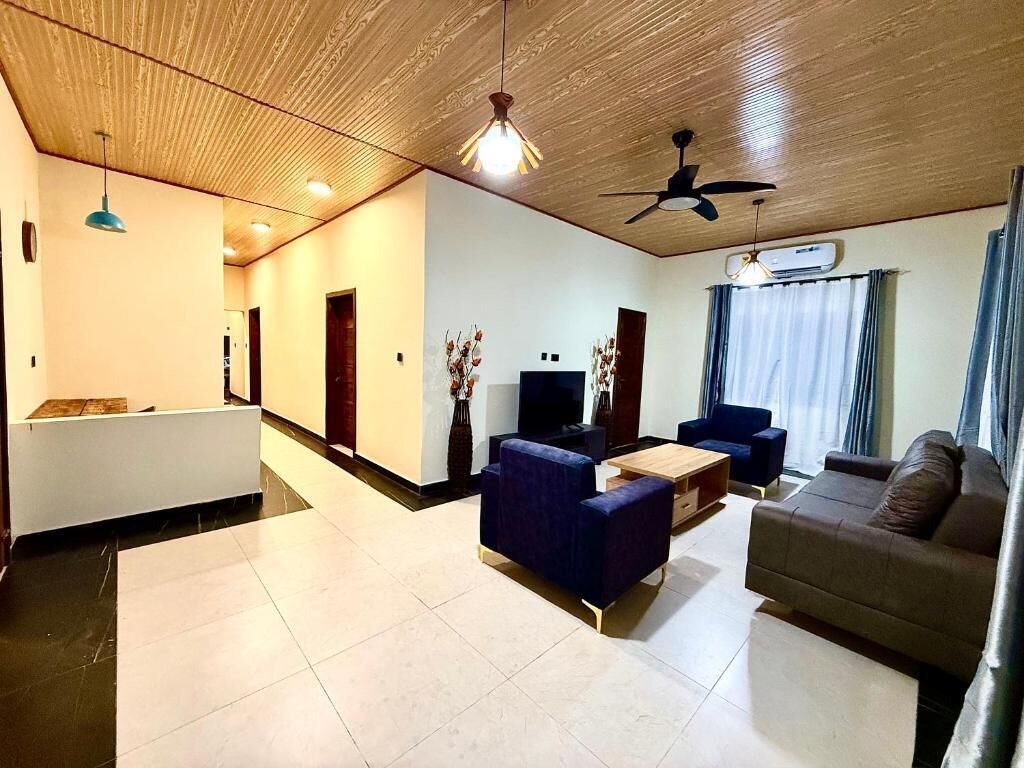 A living room with a sofa, a coffee table, and a television. There is a ceiling fan and a light fixture.