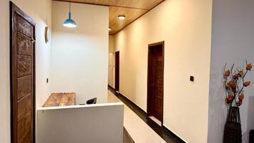 A reception area with a reception desk, wooden doors, a clock, and a vase with flowers.