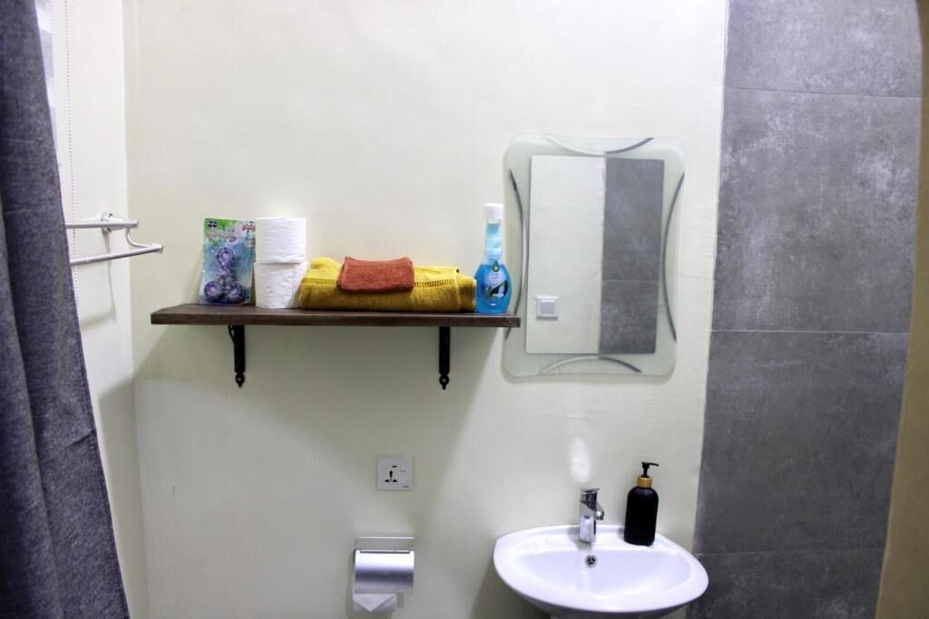 A bathroom with a white sink, a mirror, a towel rack with towels, and a soap dispenser.