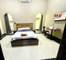 Una camera d'albergo con un letto, un tavolino con una sedia e una TV fissata al muro.