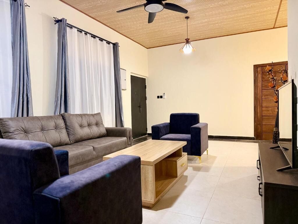 Un salon moderne comprenant un canapé, des fauteuils, une table basse et un téléviseur.
