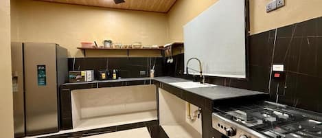 Una cocina moderna con suelo de baldosas blanco y negro, estufa empotrada y ventilador de techo.
