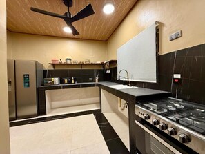A modern kitchen with a black and white tiled floor, a built-in stove, and a ceiling fan.