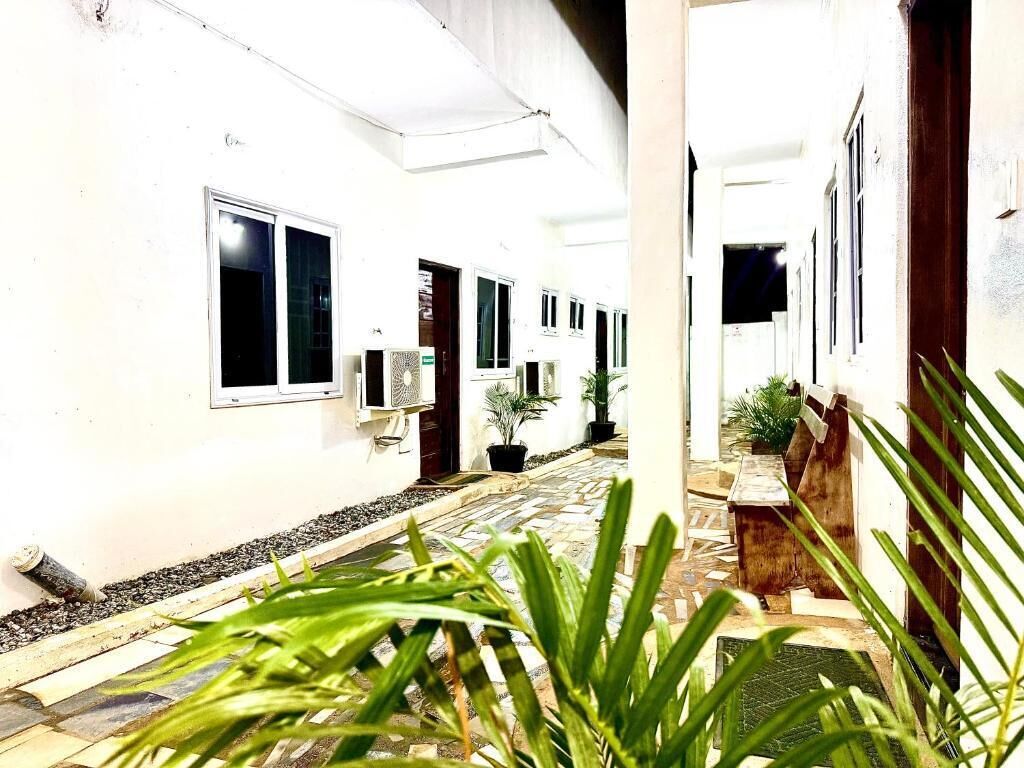 A corridor with white walls, potted plants, and a tiled floor.