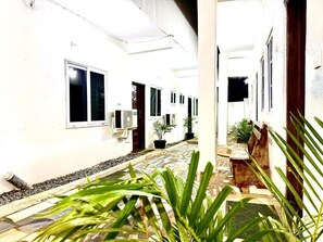 A corridor with white walls, potted plants, and a tiled floor.