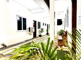 A corridor with white walls, potted plants, and a tiled floor.