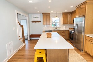Una cocina moderna con armarios de madera, un refrigerador de acero inoxidable y una isla central.