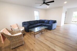 A living room with a sectional sofa, a glass coffee table, and wicker chairs. - Walk to Harborside & Marina|Sleeps 16|Boat Trailer Parking|Minutes to OC Beach (Ocean City)