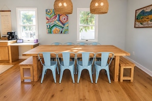 A dining area with a wooden table and blue chairs, a coffee station, and artwork on the walls. - Walk to Harborside & Marina|Sleeps 18|Boat Trailer Parking|Minutes to OC Beach (Ocean City)