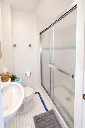 Un baño con inodoro, bidé y zona de ducha con puerta de vidrio.