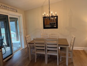 A dining area with a table and chairs, a chandelier, and a view through a glass door.