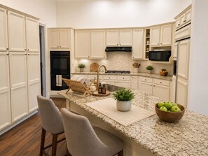 A kitchen with white cabinetry, a granite countertop, a built-in stove, and a microwave.