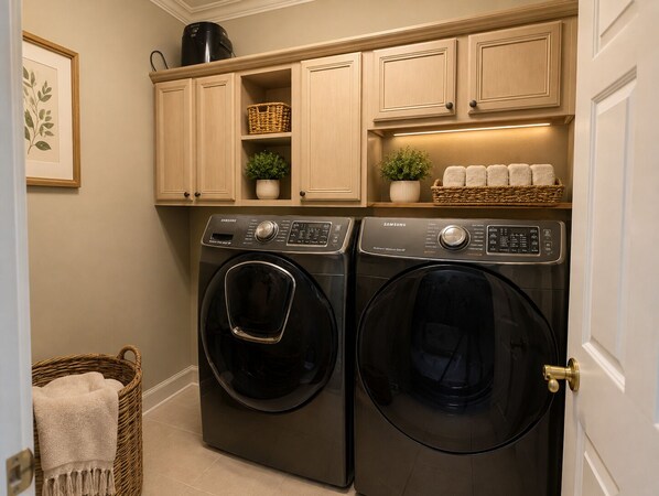 A laundry area with two front-loading washers, wooden cabinets above, and a basket with towels.