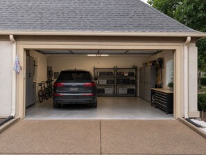 A garage with a car parked inside, a bicycle, and storage cabinets.