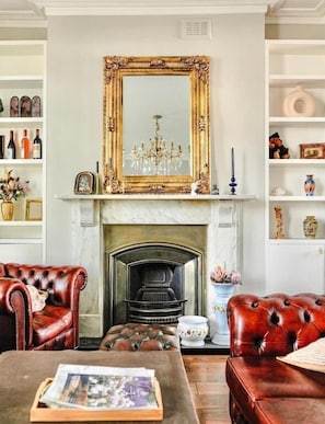 A room with a fireplace, leather sofas, a coffee table with a magazine, and a large ornate mirror above the mantel. - Angel en-suite rooms (London)